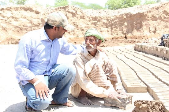 Grace Charity School staff speaking with a man at a brick kiln